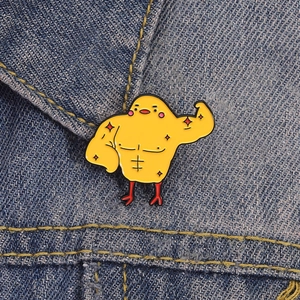 Insigne créatif poussin jaune musclé en émail sur un fond de tissu en denim bleu