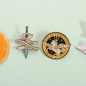 Percy Jackson sword and Pegasus enamel pin set on a mint background with orange decor