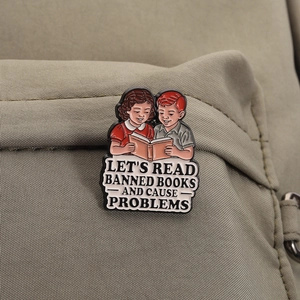 Détail du pin's émaillé rétro sur sac en toile avec texte 'Let's Read Banned Books'