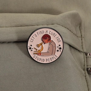 Funny enamel microscope brooch pin featuring Let's Find A Cure For Stupid People slogan