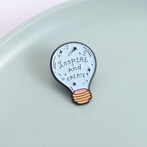 Light blue enamel bulb brooch with Inspire And CREATE quote on green ceramic plate