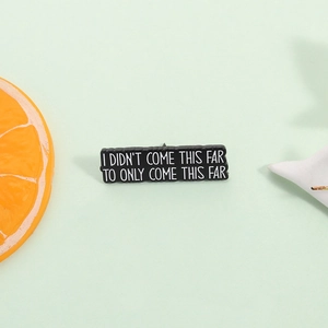 Broche rectangulaire en émail noir avec citation inspirante blanche sur fond vert pastel