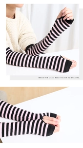 Detail of pink and black striped knit arm warmers with thumb holes and long sleeve style