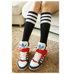 Nahaufnahme von Retro-Baumwollsocken mit drei weißen Streifen und hohen Turnschuhen