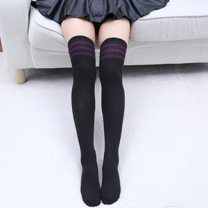 Détail de chaussettes hautes noires avec trois rayures mauves en maille de coton