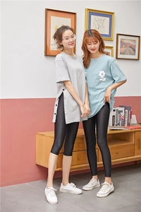 Detail view of glossy black leggings with side button accents and stretch fabric texture
