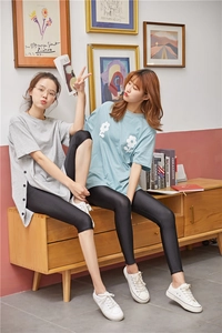Detail view of women's black glossy leggings and capri pants worn by two female models