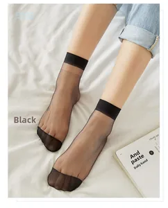 Close-up of thin black transparent ankle socks with reinforced toe on a white bed sheet
