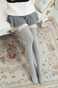 Close-up of grey over-knee cotton socks with white lace trim and vertical knit pattern