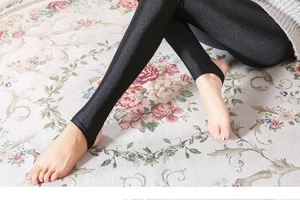Detail of high-gloss black stirrup leggings with reflective finish and elastic fabric