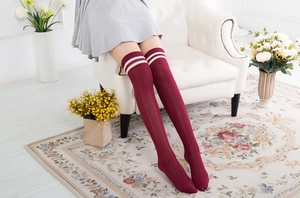 Detail von weinroten Overknee-Socken mit weißen Streifen und vertikalem Strickmuster