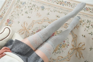 Detail von grauen Overknee-Socken mit Zopfmuster-Strick und weißer Spitzenborte am Rand