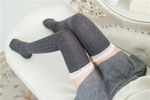 Detail of dark grey cable knit over-knee socks with white lace trim for women