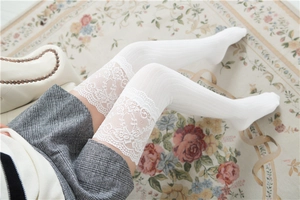 Detail von weißen Overknee-Strümpfen mit eleganter floraler Spitze und vertikaler Textur