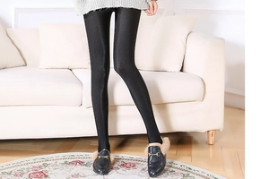 Detail of black glossy leggings with silky finish shown in a cozy home setting