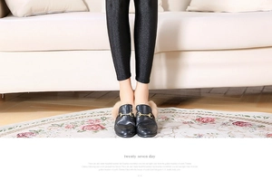 Detail of black leather mule shoes with gold horsebit buckle and fur lining on leggings