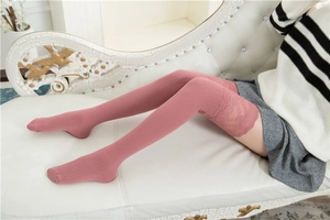 Detail rosa Overknee-Baumwollsocken mit breitem Spitzenbesatz auf Vintage-Sofa