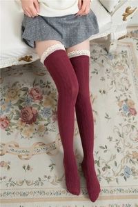 Detailed close-up of dark burgundy cable knit over-knee socks with white lace trim