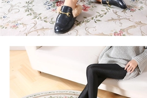 Detail of glossy black elastic leggings paired with golden horsebit buckle loafers