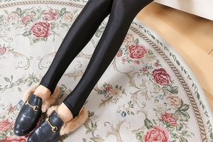 Close-up of shiny black high-elastic leggings with glossy finish on vintage rug