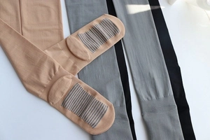 Close-up of three compression tights in beige, grey and black with reinforced sole detail