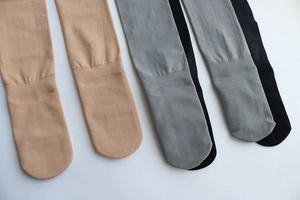 Close-up of ribbed knit texture on toe and ankle of skin-tone, grey, and black tights