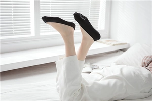 Close-up of black low-cut no-show socks with silver rose pattern in a bright room