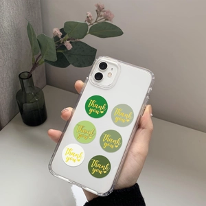 Detailed view of clear phone case decorated with green and beige Thank You stickers