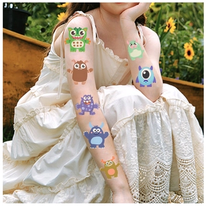 Colorful cartoon monster temporary tattoo stickers on a child arm in a garden