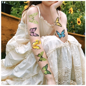 Detailopname van kleurrijke vlindertattoos op de arm van een kind in een tuinsetting
