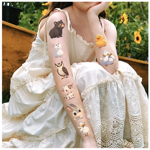 Detail of cute cartoon animal temporary tattoos applied on model arm in a sunny garden