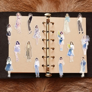 Detailed view of fashion girl stickers displayed on a craft paper notebook page