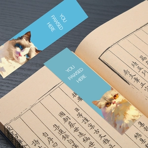 Detail of cute cat bookmarks with 'You Pawsed Here' text on an open vintage book page