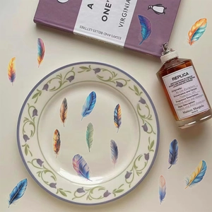 Disposition artistique d'autocollants plumes colorées sur une assiette en céramique