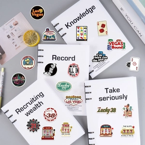 Flat lay of Las Vegas casino stickers with slot machines and poker cards on notebook