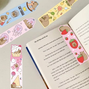 Close-up of five colorful cartoon Capybara bookmarks on an open English book page