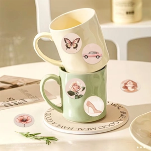 Detail of vintage floral stickers applied on stacked cream and green ceramic mugs