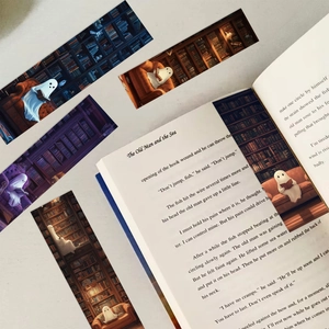 Close-up of ghost reading bookmarks with dark library illustrations tucked into a book