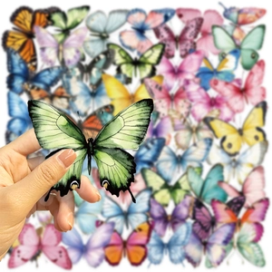 Close-up of a hand holding a green butterfly sticker with colorful stickers background