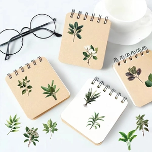 Flat lay of green leaf PET stickers and spiral notebooks with floral illustrations