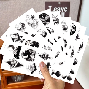 Close-up of realistic black temporary tattoos featuring mountains, forests, and waves