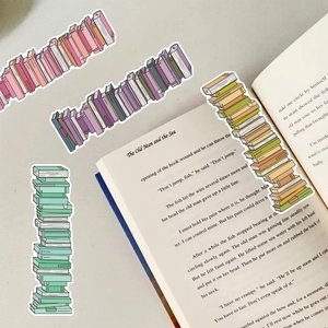 Detail of artistic book-shaped stickers stacked on a vintage book page backdrop