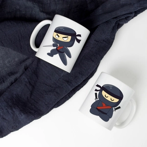 Détail de deux mugs en céramique blanche avec des illustrations de ninjas sur tissu bleu plissé