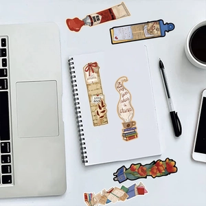Close-up of vintage aesthetic bookmarks with coffee and book illustrations on a white desk