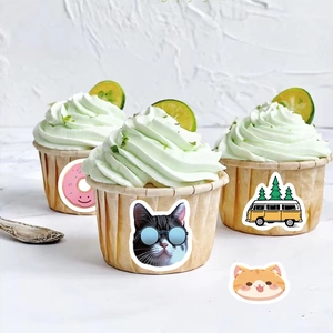 Close-up of decorative cartoon stickers with cat and donut designs on cupcakes