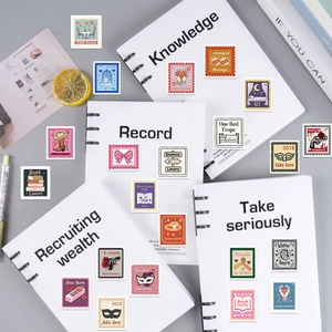 Detail of vintage stamp-style bookish stickers on white notebook for DIY scrapbooking decor