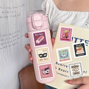 Close-up of vintage aesthetic literary stamp stickers on a book and water bottle