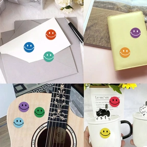 Detail of colorful smiley face stickers applied on envelope, book, guitar and mug surfaces