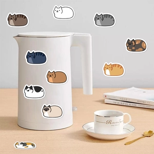 Autocollants de chats mignons décorant une bouilloire et un mug sur un bureau en bois