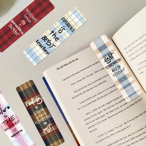 Détail de cinq marque-pages à carreaux avec des citations inspirantes sur un livre ouvert